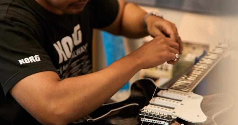 Technician restringing guitar strings – guitar care tips