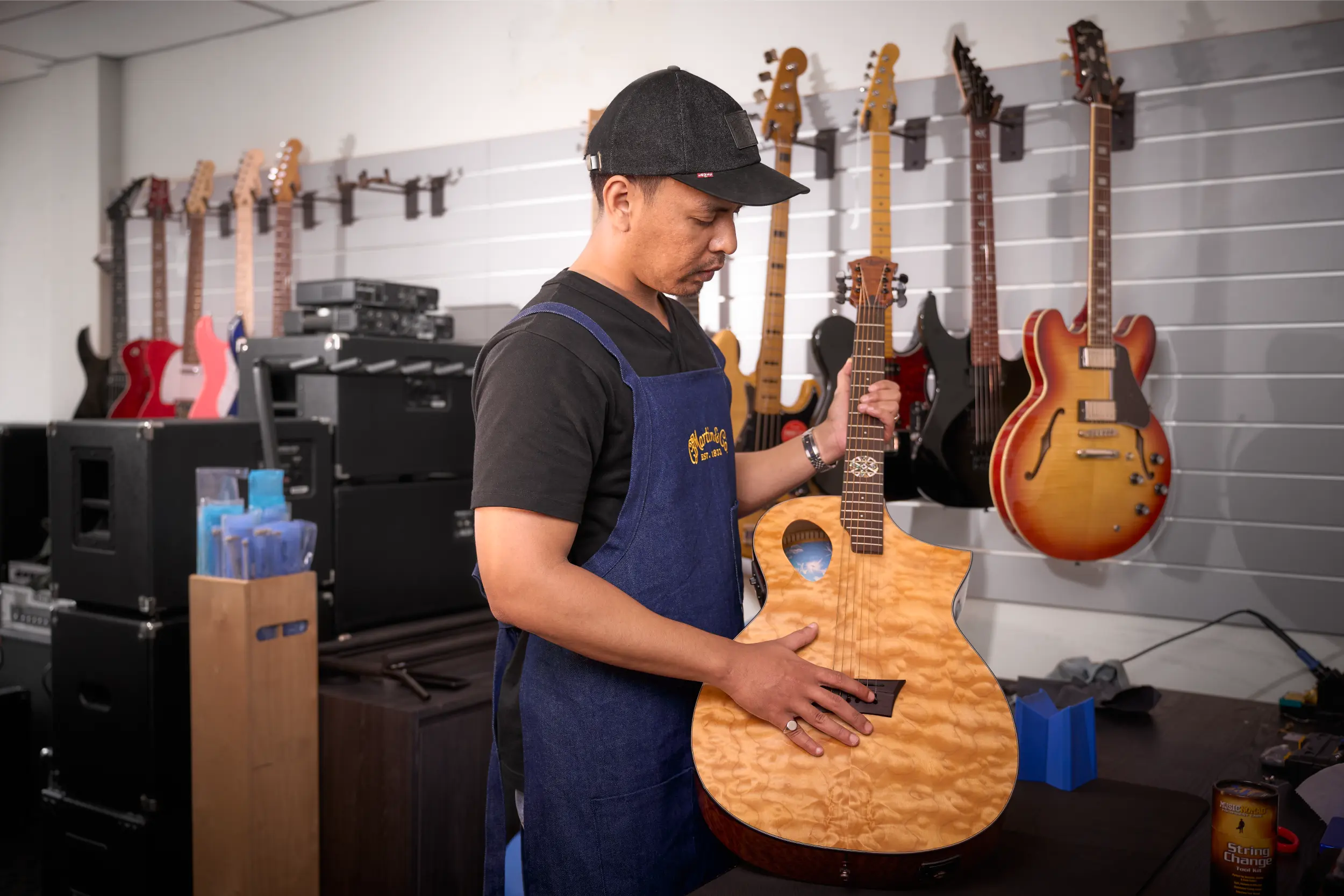 Guitar technician in Malaysia inspecting hardware, electronics, and fretboard health.