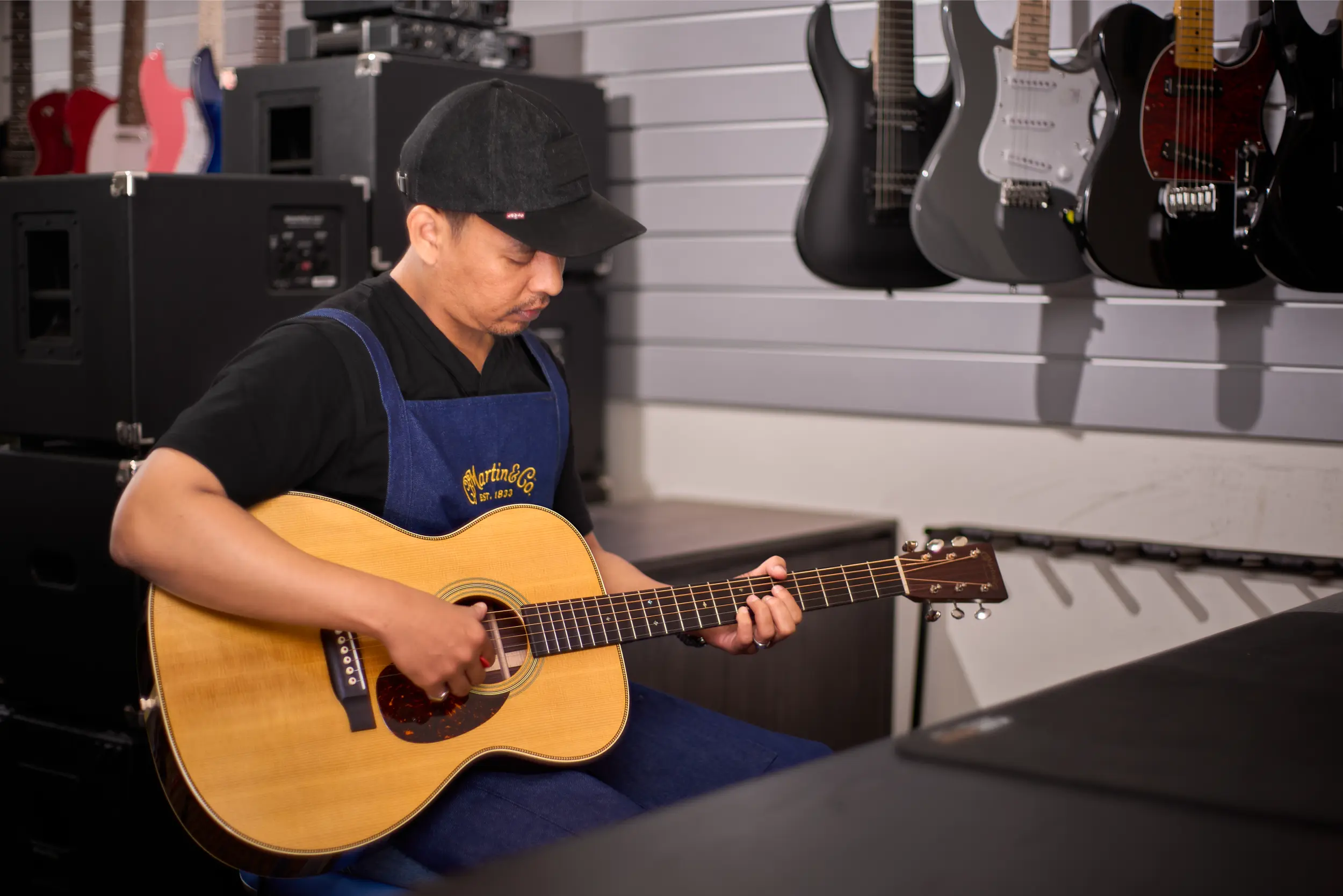 Technician in Malaysia play-testing a guitar to check intonation and electronics after service.