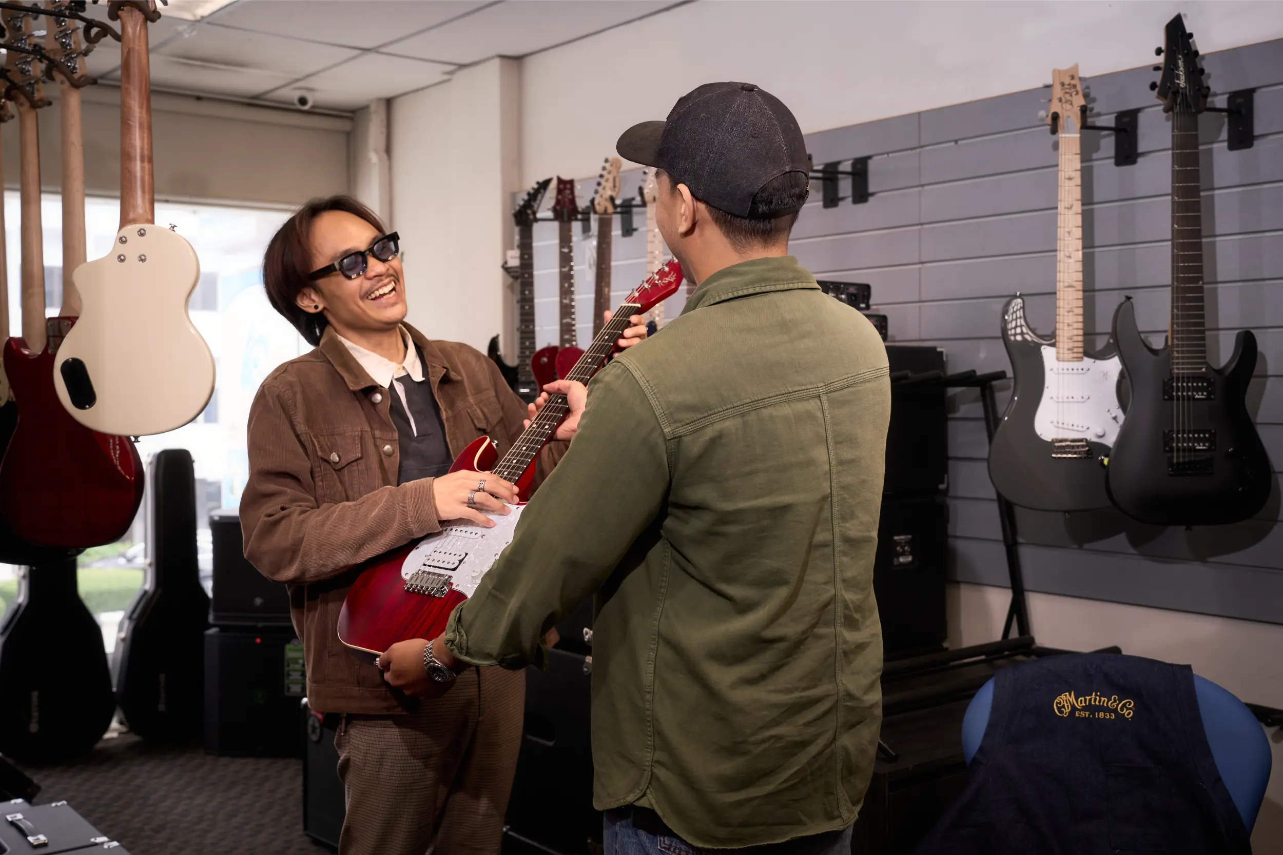 Technician in Malaysia handing over a serviced guitar to customer at CK Music.