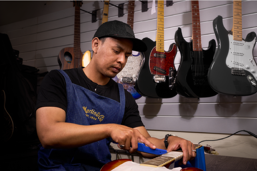 Guitar technician crowning frets on an electric guitar in Malaysia.